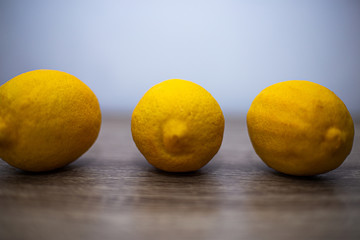 Three large whole lemons lie on a wooden table