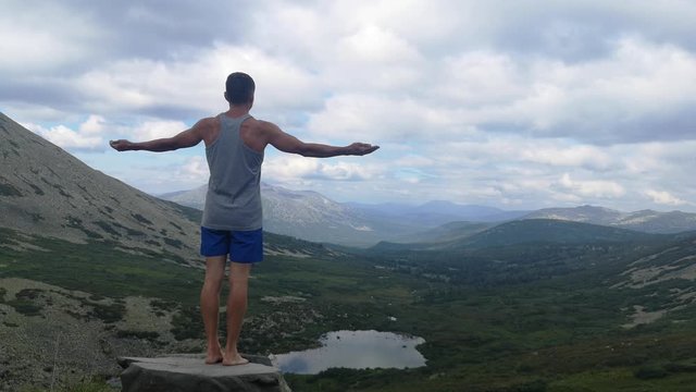 man stands on top of a mountain with open hands. at the top of the mountain, a man with his arms spread wide.