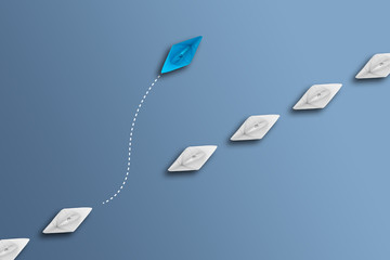 white paper boats in a row on blue background and one paperboat going in different direction,...