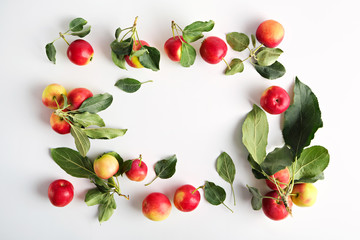 Red and yellow ripe apples with leaves close-up in a wicker basket on a light background top view. copy-space. No people. 