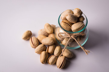 Pistachios in glass bottles on white background. Copy space.