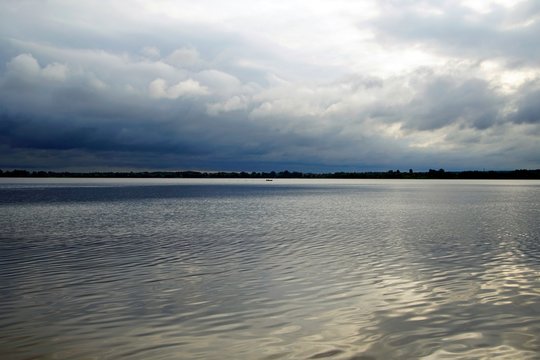 Cloudy day at Lake Lepel. Dark rain clouds and reflection on the water surface. Horizon and space.