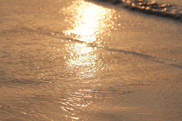 Sun glare on water surface at sunset, golden waves, texture