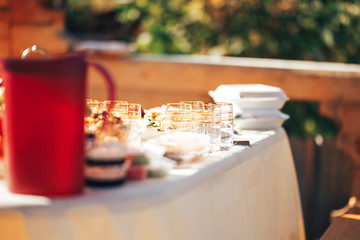 Long table covered with a tablecloth on which there is a lot of food, food in plates