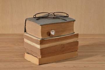 Libros antiguos sobre una mesa vieja y lentes graduadas	