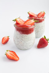 Pudding with chia and  strawberry  in the  two glass jars on the white background. Closeup. Location vertical.