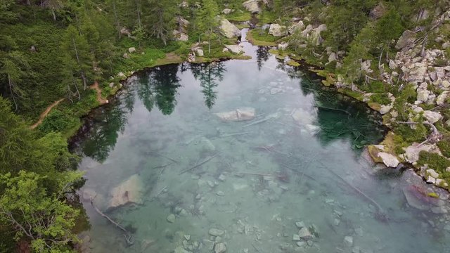 Italy  Piedmont,  Devero village  , ( lago delle streghe )  Alps - caucasian girl do trekking , hiking in a wood mountains, 
Lake of witches  with clear water in a wild landscape of nature