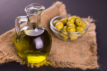 Olive oil in a decanter and fresh olives on the table.
Close-up.