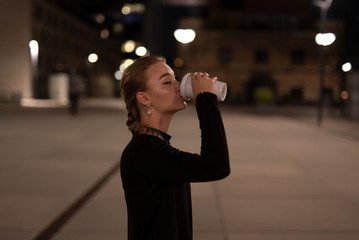 Fototapeta premium Junge Frau mit einem Kaffee in der Hand. Junge Frau mit einem Kaffebecher in der Hand. Junge Frau trinkt einen Kaffe.