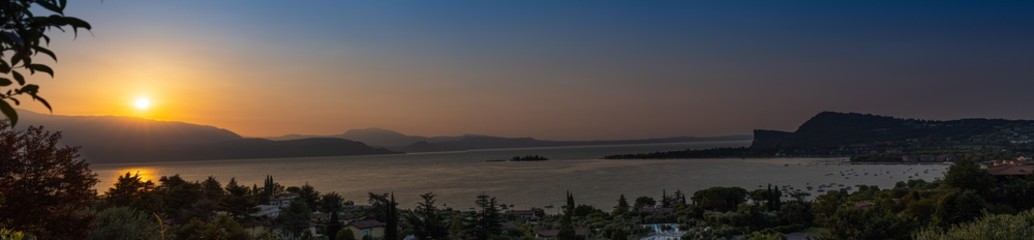 Fototapeta na wymiar Sunrise in Manerba del Garda with the silhouettes of the mountains in the background on Lake Garda, Italy