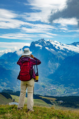 Eiger, Switzerland;  A woman photographing the the view of the village of Grindelwald and Jungfrau in the Swiss Alps.