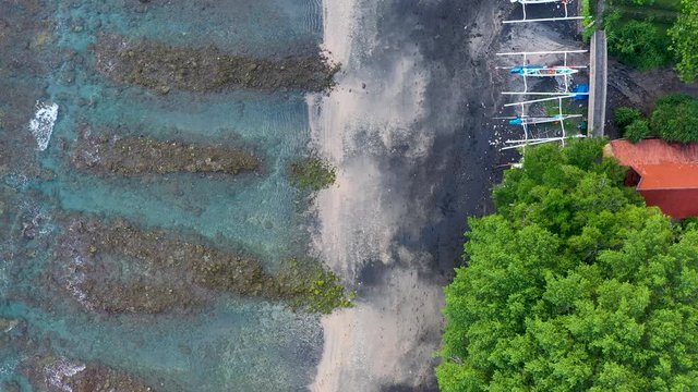 The tropical bay beach with sand and stones. Village with boats in Amed, Bali.