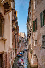 Fototapeta na wymiar Beautiful venetian street in summer day, Italy - Gondola riders