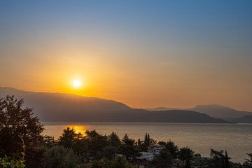 Fototapeta premium Sunrise in Manerba del Garda with the silhouettes of the mountains in the background on Lake Garda, Italy