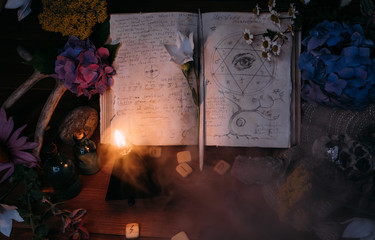 Open old book with magic spells, runes, black candle