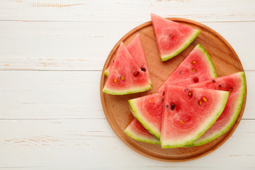 Fresh ripe striped sliced watermelon on cutting board on white wooden background.