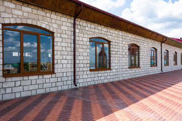 Colored red paving slabs and brown pvc metal-plastic windows. Construction of the park.