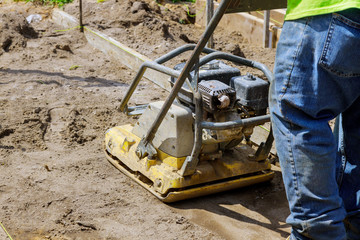 Worker uses compactor to vibratory hammer power tool at construction site