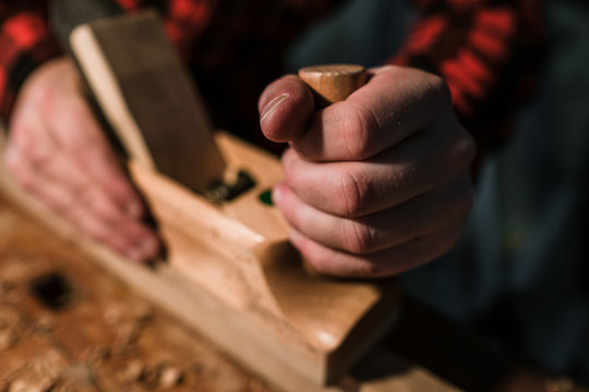 Hand hält Hobel während des hobelns eines Stück Holzes