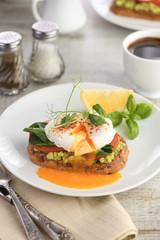 Eggs Benedict with guacamole on cereal bread