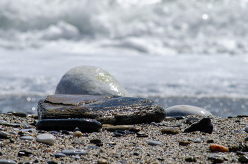 Selective focus shot of small stones at the border of a wavy sea