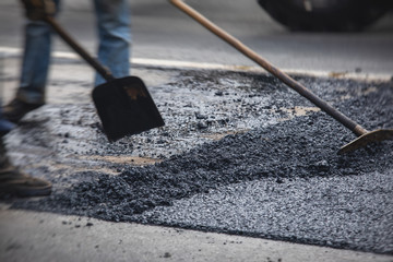 Asphalt paver machine and steam road roller during road construction and repairing works, process of asphalting and paving, workers working on the new road construction site, placing a layer