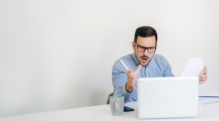 Angry disagreeable businessman sitting at the desk talking online video conference call making...