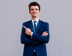 Young handsome businessman with beaming smile pointing with finger