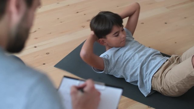 Family fitness at home, Father coach, Sports kid, Fun gymnastics. Dad trainer records athletic performance while son does physical exercise
