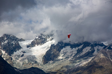 A paraglider sails over the  Ober Gabelhorn (4063 m).  It is a mountain in the Pennine Alps in Switzerland, located between Zermatt and Zinal.