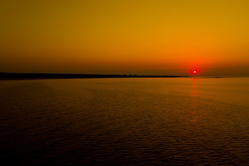 Naklejka premium Aerial photo from flying drone of a fascinating nature landscape with dramatic evening sunset sky which reflected in sea water with calm waves. Beautiful scenery of a Indian Ocean with sunrise