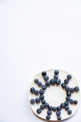 sun made of blueberries on white plate on the white background. top view