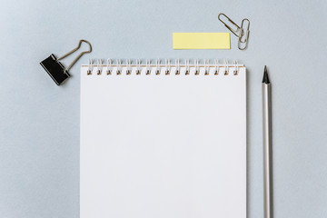 Flat layout of office workplace with stationery. Blank stickers with place for text, pencils, notebook, binder clips and pushpins isolated on white and blue background. Office supplies set.