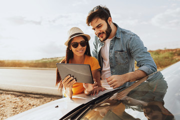 Family road trip. Latin family traveling locally by car. Using map on tablet for navigation