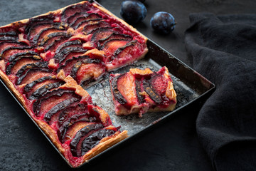 Traditioneller französischer Tarte aux Prunes mit süssen Pflaumen angeboten als close-up auf einem rustikalen Metall Tablett