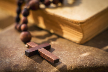 Rosary cross against Bible background as a symbol of victory over death.