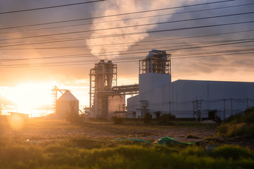 Fototapeta na wymiar Sunset over Industrial pipe building of fiberboard factory working with release smoke from chimney
