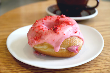 Mouthwatering strawberry-glazed with raspberry cream filling doughnut on a white plate