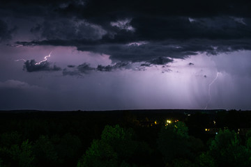 Lightning strike in the dark night sky. Summer thunderstorm.