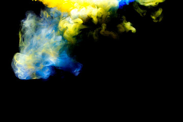 A cloud of yellow and blue paint released into clear water. Isolate on a black background.