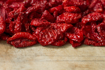 Close-up sun-dried tomatoes with spices and olive oil on wooden cutting board, background or concept, selective focus