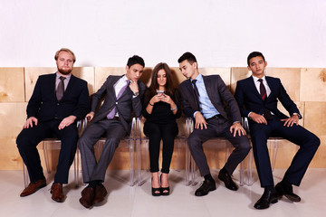 Young business woman with her partners reading text on mobile phone while they waiting for the meeting, successful female financier chatting on cell telephone while sitting in hallway big company