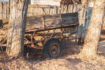 Old car trailer abandoned and falling apart fence. Desolation, extinction of the village.