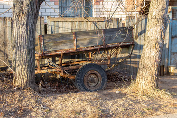 Fototapeta na wymiar Old car trailer abandoned and falling apart fence. Desolation, extinction of the village.