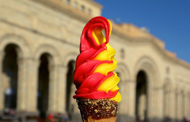 Yellow Pineapple with Red Raspberry Flavored Soft Serve Ice Cream Cone Against Blurry Vintage Building