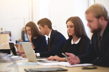 Multi ethnic group of professional programmers is working on laptop computers, while are sitting in modern office interior. International students are using portable net-book for preparing to exams