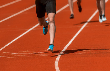Athletics people running on the track field. Sunny day