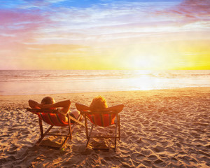 happy couple on the beach vacation, holidays getaway travel, silhouettes of man and woman sitting...
