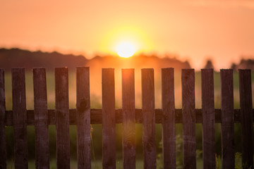 the setting sun sets behind the fence in the field