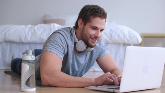 Family fitness at home, Father coach, Sports kid, Fun gymnastics. Man using laptop while lying on the floor at home getting ready for online fitness